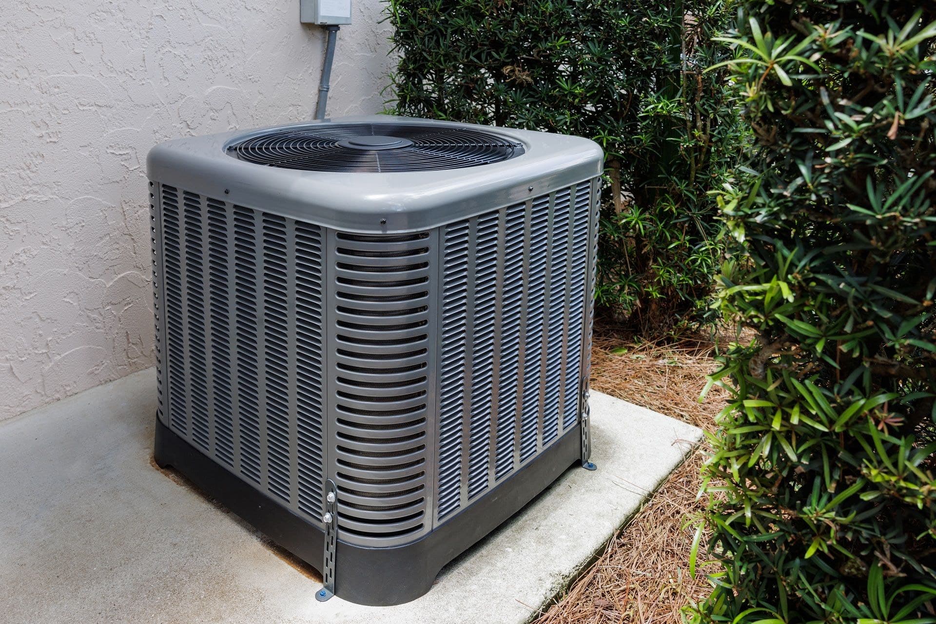 Outdoor air conditioning condenser beside a home