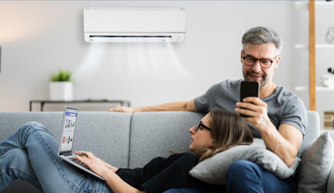A couple relaxing at home beneath a ductless mini-split head